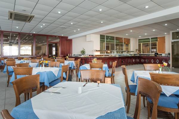 Innenansicht des Restaurants im Astir Palace Hotel mit blauen Tischdecken und holzigen Stühlen.