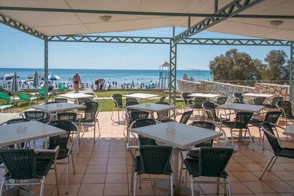 Terrasse des Astir Palace Hotels mit Tischen, Stühlen und Blick auf den Strand.