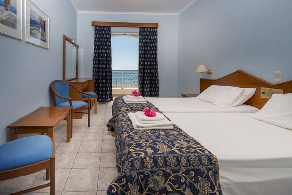 Zimmer im Astir Palace Hotel mit zwei Betten, Blick auf das Meer, gerahmte Bilder an der Wand.