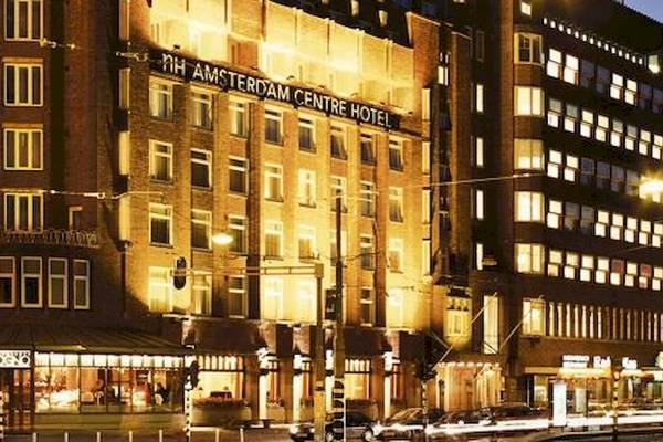 Das NH Amsterdam Centre Hotel ist nachts beleuchtet und steht an einer belebten Straße.