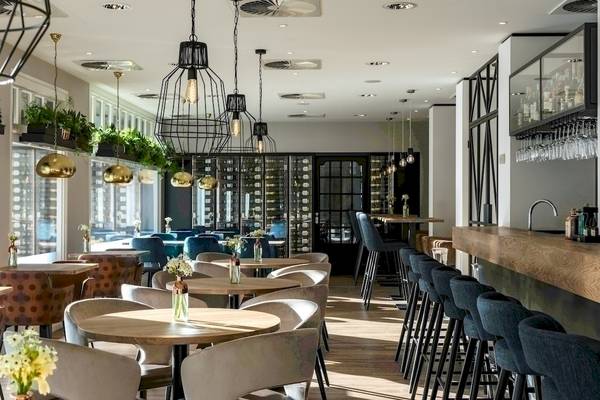 Innenbereich des NH Amsterdam Centre Hotels mit Tischen, Stühlen und Bar.