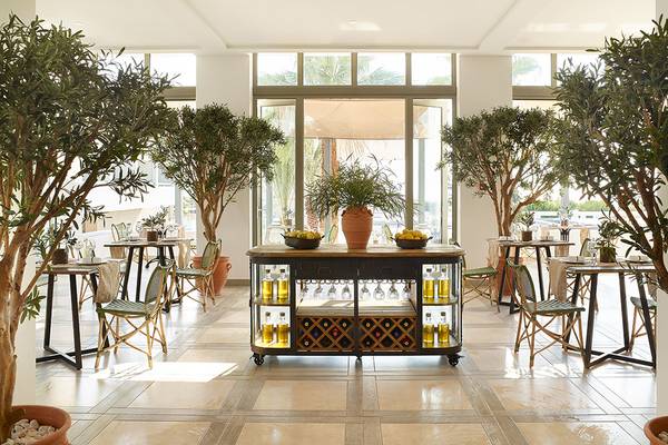 Innenbereich des Restaurants im Grecotel Lux Me Dama Dama mit großen Bäumen, Tischen und Stühlen.