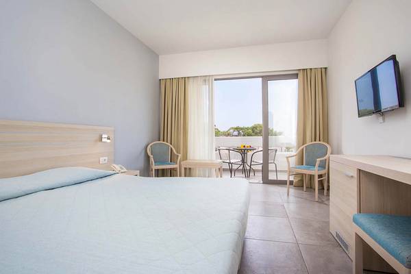 Zimmer im Niriides Beach Hotel mit Bett, Schreibtisch und Balkon