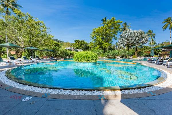 Ein Swimmingpool im Duangjitt Resort & Spa mit umliegenden Liegestühlen und grünen Pflanzen.