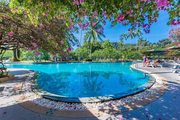 Ein Swimmingpool des Duangjitt Resort & Spa mit Palmen und blühenden Bäumen