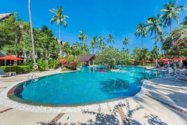 Poolbereich im Duangjitt Resort & Spa mit Liegestühlen und roten Sonnenschirmen.