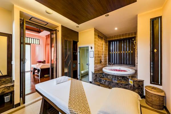 Massageraum im Duangjitt Resort & Spa mit einem großen Whirlpool und einem Behandlungstisch.
