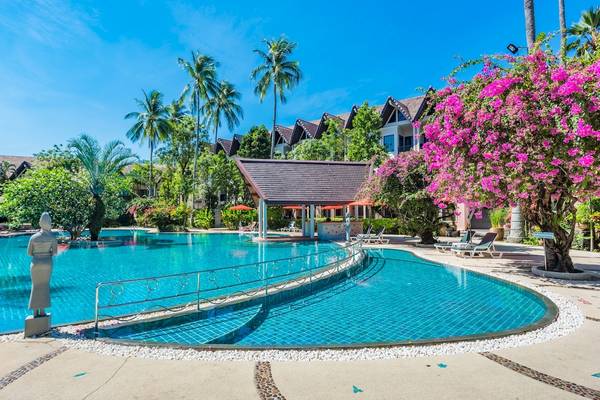 Poolbereich des Duangjitt Resort & Spa mit Sonnenliegen und Palmen