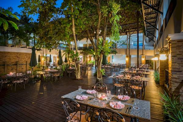 Foto des Außenbereichs des Duangjitt Resort & Spa Restaurants mit beleuchteten Tischen und Stühlen.