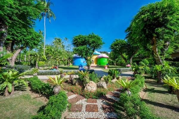 Außenansicht des Duangjitt Resort & Spa Gartens mit bunten Spielhäusern und grünen Pflanzen