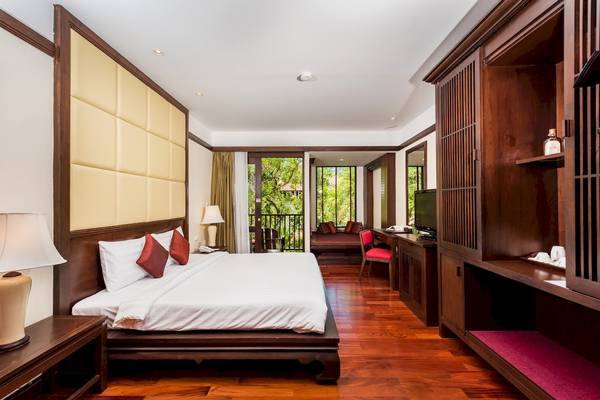 Hotelzimmer im Duangjitt Resort & Spa mit einem großen Bett, Holzboden und einem Balkon.