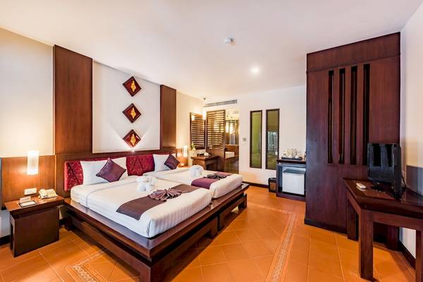 Ein modernes Hotelzimmer im Duangjitt Resort & Spa mit zwei Betten, Dekor und Einrichtung.
