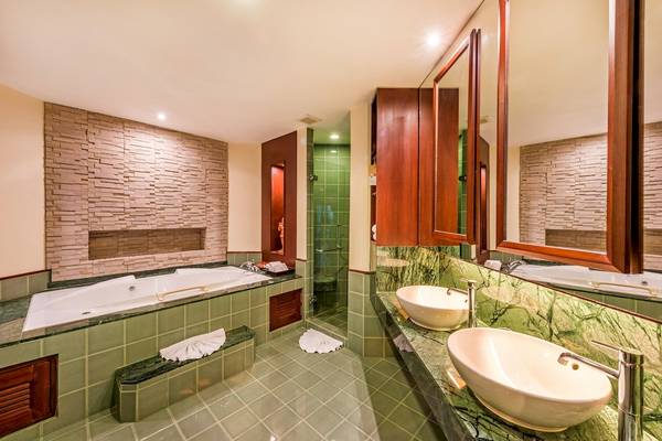 Badezimmer im Duangjitt Resort & Spa mit Badewanne, Spiegeln und grünen Fliesen.