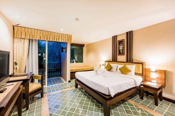 Hotelzimmer im Duangjitt Resort & Spa mit Bett, Schreibtisch, Fernseher und Balkon.