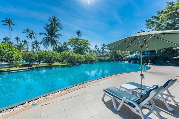 Außenpool des Duangjitt Resort & Spa mit Sonnenliegen und Sonnenschirm.