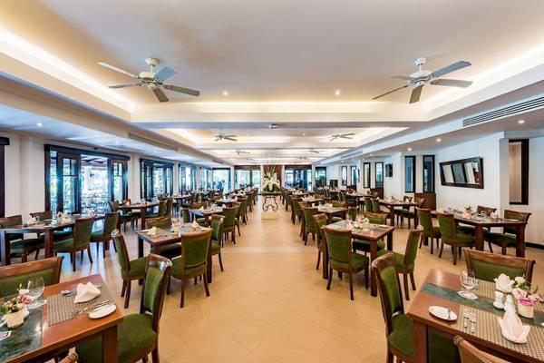 Innenansicht des Restaurants im Duangjitt Resort & Spa mit gedeckten Tischen und Stühlen.