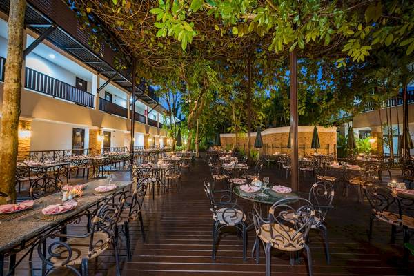 Außenbereich zum Abendessen im Duangjitt Resort & Spa mit gedeckten Tischen und abendlicher Beleuchtung.