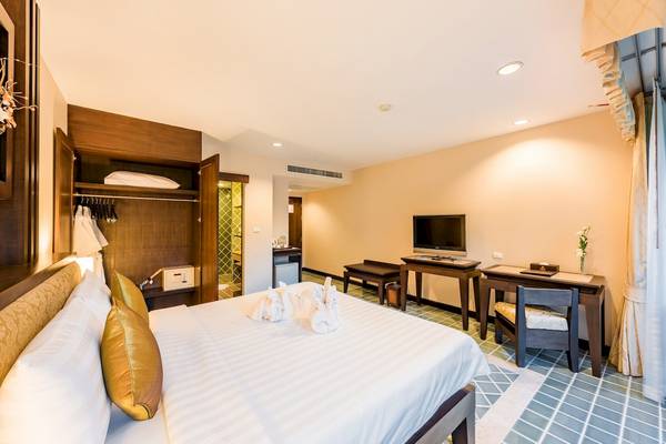 Innenansicht eines Hotelzimmers im Duangjitt Resort & Spa mit Bett, Schreibtisch, Fernseher und Kleiderschrank.