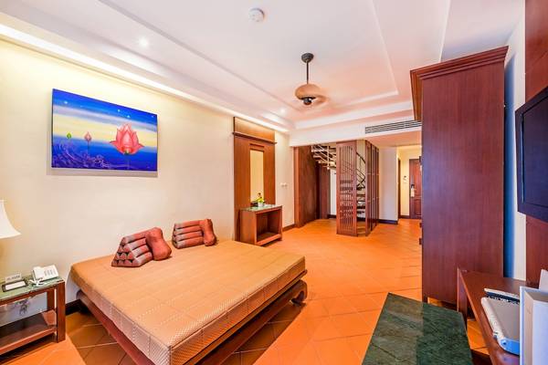 Innenansicht des Schlafzimmers im Duangjitt Resort & Spa mit Bett, Kissen und Dekor.