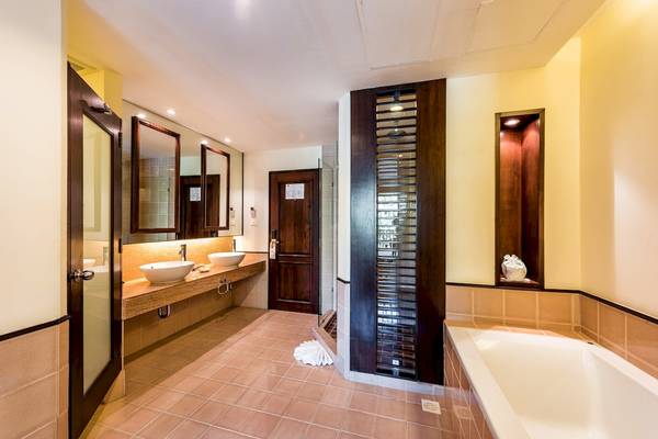 Badezimmer im Duangjitt Resort & Spa mit zwei Waschbecken, Badewanne und Dusche.