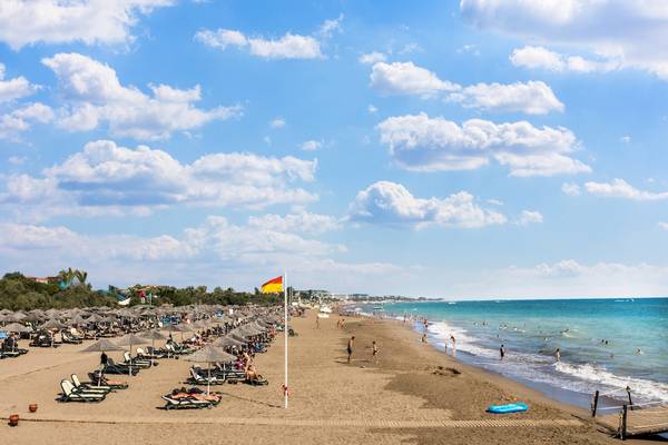 Strand des Asteria Family Resort Belek mit vielen Liegen, Sonnenschirmen und Gästen