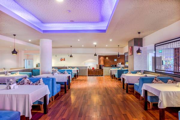 Innenansicht des Restaurants im Asteria Family Resort Belek mit blauen Stühlen und Holzboden.