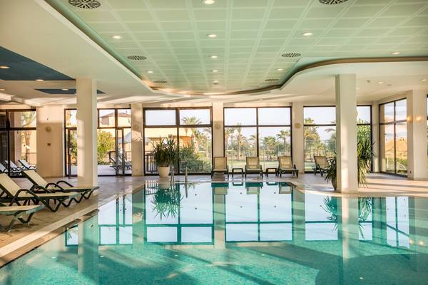 Poolbereich im Asteria Family Resort Belek mit Sonnenliegen und großen Fenstern.