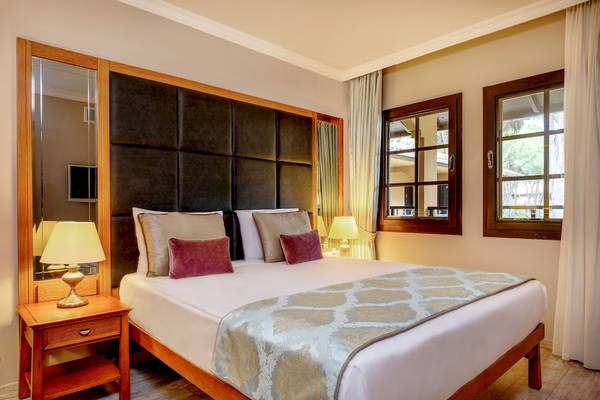 Hotelzimmer im Asteria Family Resort Belek mit gepolstertem Kopfteil und Fenstern.