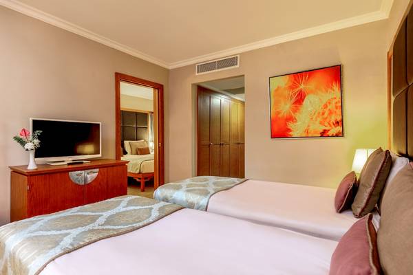 Doppelzimmer im Asteria Family Resort Belek mit zwei Betten, Fernseher und Dekor.