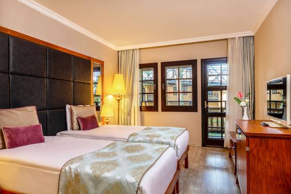 Doppelzimmer im Asteria Family Resort Belek mit zwei Betten, Nachttischen, Lampen und einem Fernseher.