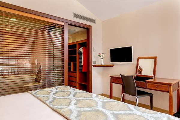 Innenansicht eines Hotelzimmers im Asteria Family Resort Belek mit Bett, Schreibtisch, Spiegel und Fernseher.