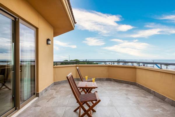 Balkon mit Meerblick im Asteria Family Resort Belek, zwei Holzstühle und ein Tisch mit Getränken.
