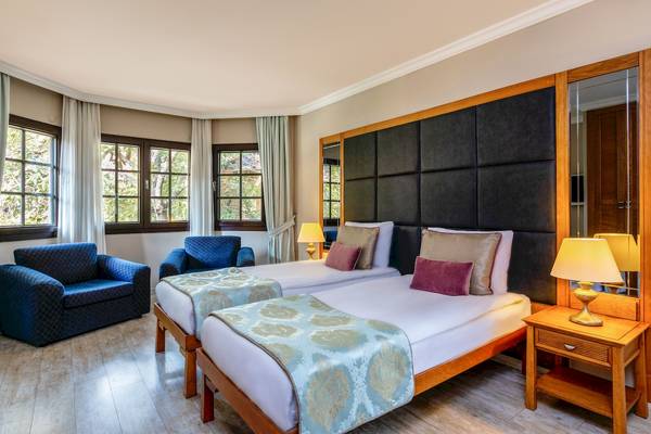 Zwei Betten im Zimmer des Asteria Family Resort Belek mit bequemen Kissen und Decken.