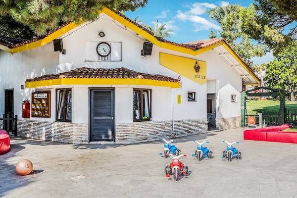 Ein Gebäude des Asteria Family Resort Belek mit einer Uhr, Fenstern und Spielzeugmotorrädern vor dem Gebäude.