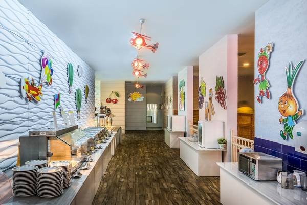Innenbereich des Restaurants im Asteria Family Resort Belek mit farbenfrohen Wanddekorationen und Holzboden.