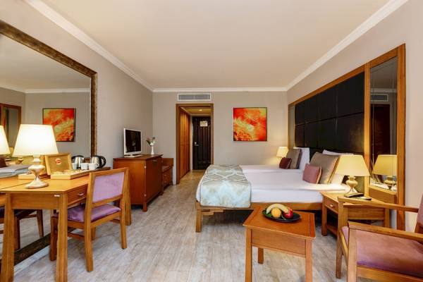 Hotelzimmer im Asteria Family Resort Belek mit Doppelbett, Schreibtisch und Esstisch.