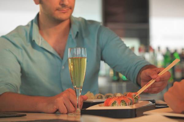 Mann trinkt Champagner während einer Sushi-Mahlzeit im Su Hotel.
