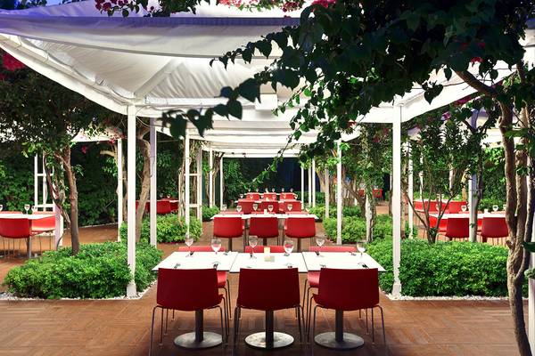 Außenbereich des Su Hotel Restaurants mit roten Stühlen und Tischen unter weißen Markisen.