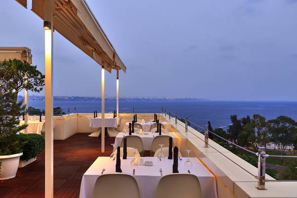 Dachterrasse des Su Hotels mit Blick auf das Meer und beleuchtete Städte in der Ferne.