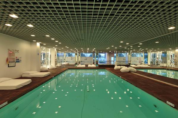 Innenpool des Su Hotels mit weißen Liegen und grünem Wasser