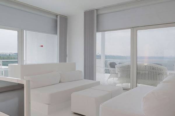 Ein elegantes Zimmer im Su Hotel mit weißen Möbeln und großen Fenstern, die einen Blick auf die Stadt ermöglichen.