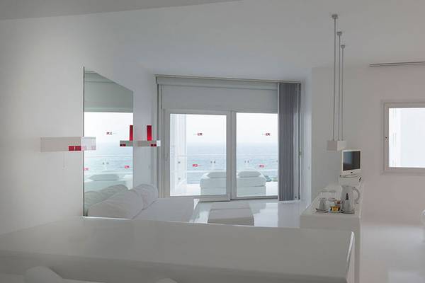 Innenansicht eines Zimmers im Su Hotel mit weißem Interieur, großem Fenster und Meerblick.