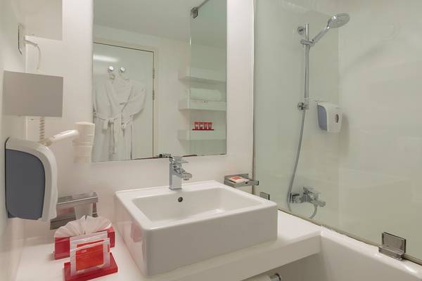 Badezimmer im Su Hotel mit weißem Waschbecken, Spiegel und Dusche.