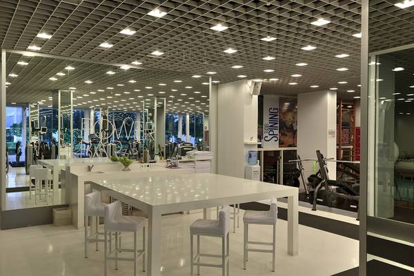 Das Fitnesscenter-Interieur des Su Hotel mit weißen Tischen und Stühlen sowie Spiegelwänden.