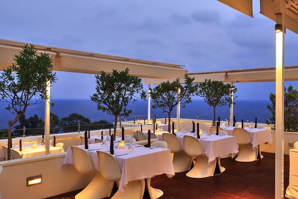 Dachterrasse des Su Hotels mit Blick auf das Meer und weißen Tischen und Stühlen.