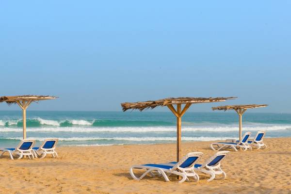 Sonnenliegen und Sonnenschirme am Strand des VOI Praia De Chaves Resort.