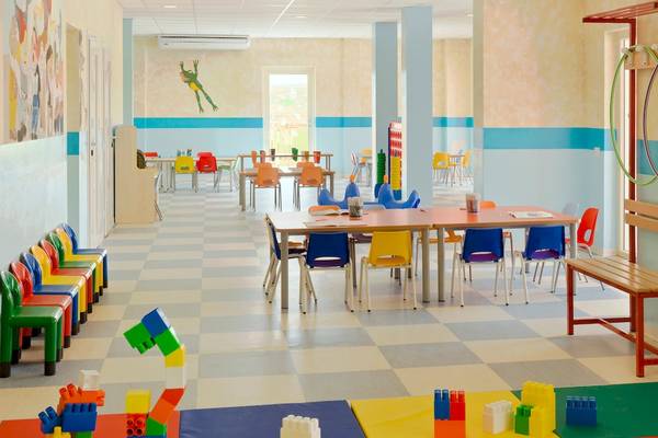 Kinderzimmer im VOI Praia De Chaves Resort mit bunten Stühlen und Tischen auf gemustertem Boden.