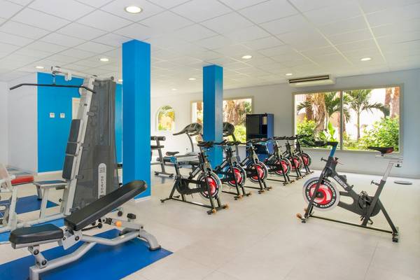Fitnessstudio im VOI Praia De Chaves Resort mit verschiedenen Geräten auf blauen Matten.