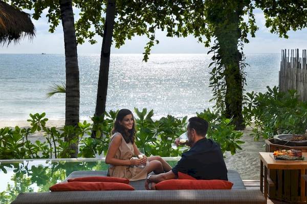 Ein Paar und ein Koch bei einem Abendessen am Strand des Anantara Rasananda Koh Phangan Villas