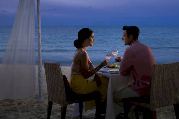 Paar sitzt an einem Tisch auf dem Strand der Anantara Rasananda Koh Phangan Villas